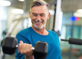 mature man using dumbbells in gym