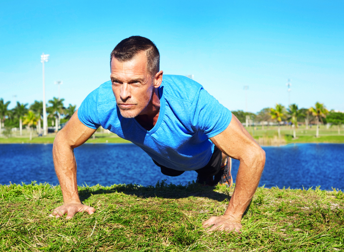 mature man performing pushups outdoors in sunshine, workout to get rid of man boobs