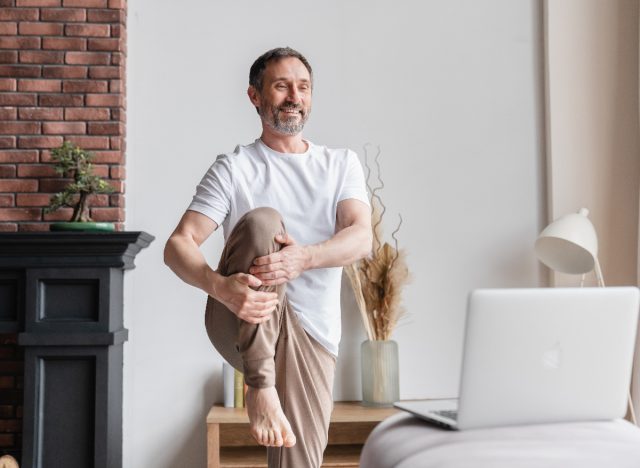 mature man stretching doing online fitness class