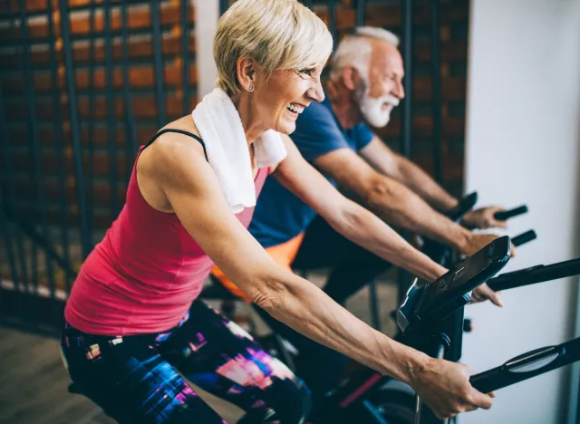 mujer madura haciendo ejercicio cardiovascular en bicicleta para acelerar la pérdida de grasa abdominal