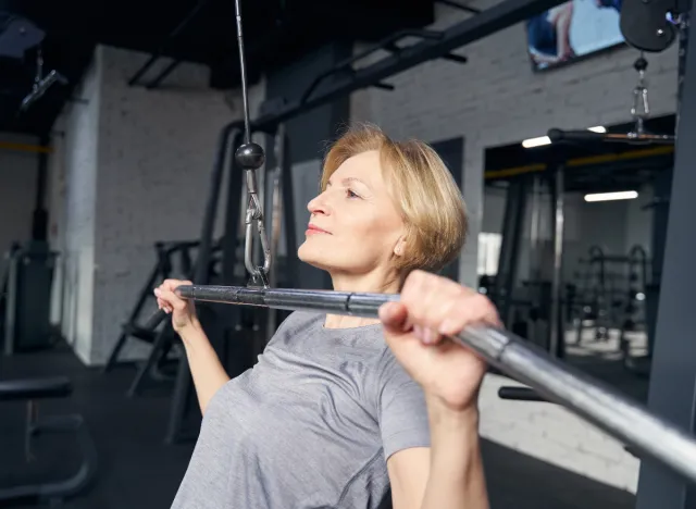 mature woman doing lat pulldown in gym