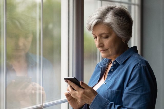 Mujer mayor enviando mensajes de texto en casa, usando una aplicación para detectar la enfermedad de Alzheimer