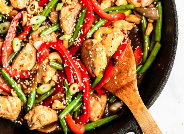 orange chicken stir fry in a skillet and wooden spoon