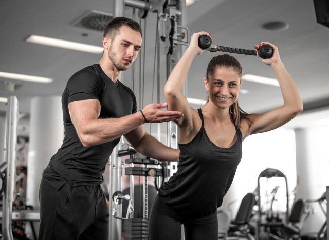 woman works on overhead rope extension with trainer, demonstrating exercise to drop weight fast