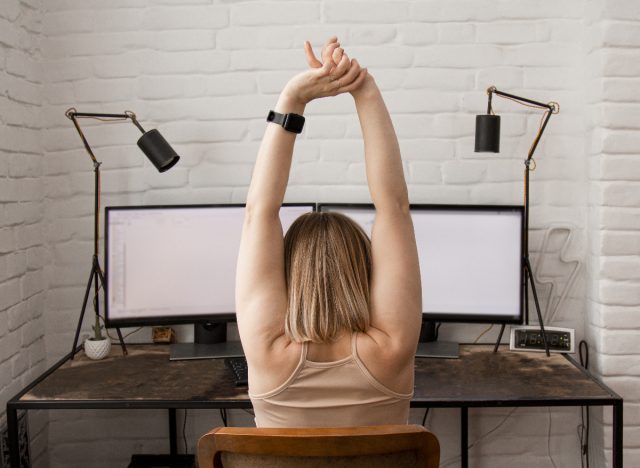 woman stretching, sedentary sitting at desk