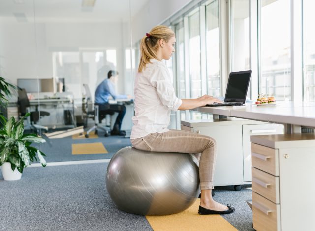 woman on stability ball desk chair to burn calories while working