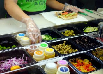 subway sandwich artist assembles sandwich