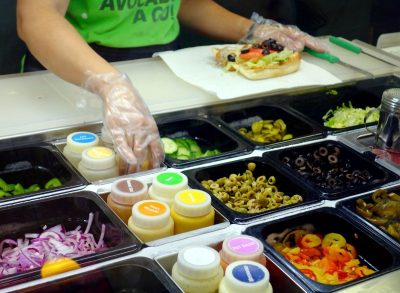 subway sandwich artist assembles sandwich