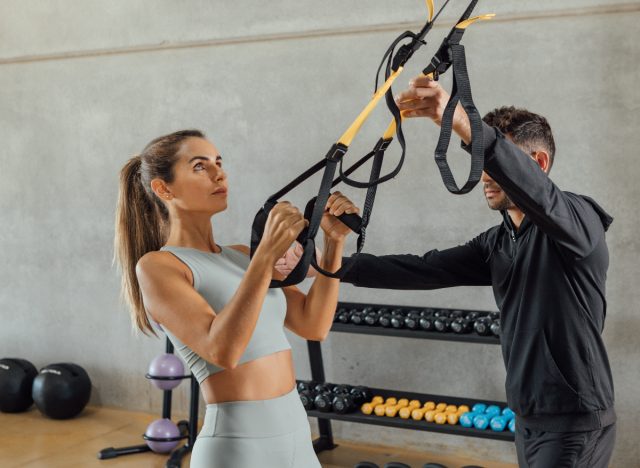 woman doing suspension strap exercise during couples workout