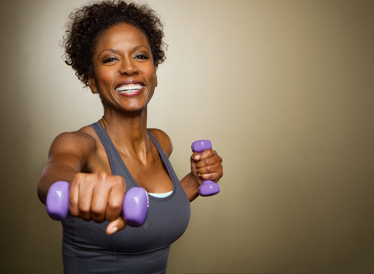 woman in her 40s performing body-shaping workout with dumbbells