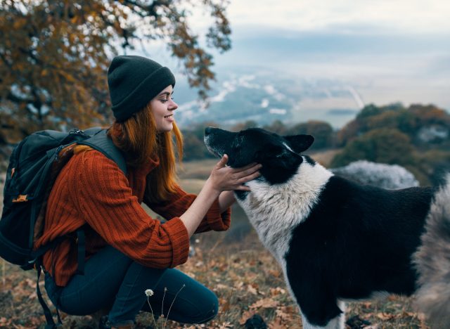 woman talking baby talk with dog, scenic backdrop in the fall