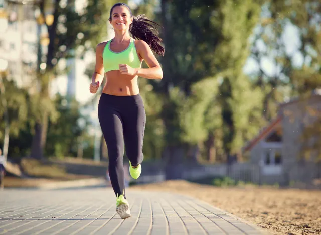 A female runner in the park showing how to jog on a lean body