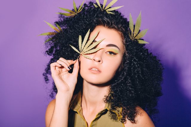 Portrait of a woman with cannabis leaf near her face