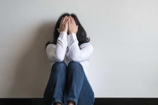 woman sitting on floor in home dealing with panic attack