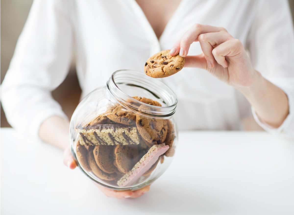 woman taking cookie from cookie jar