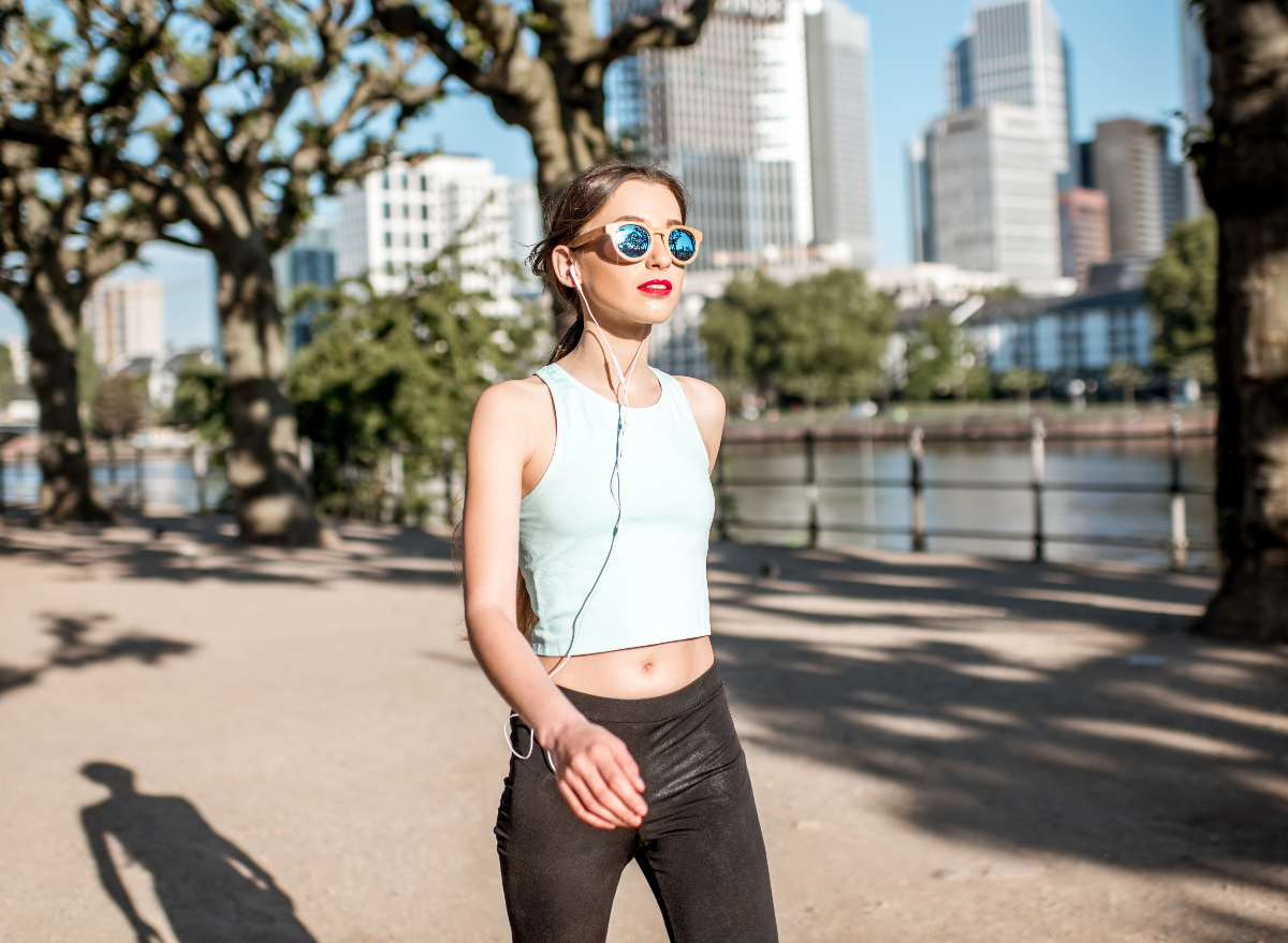 woman getting exercise in the city, demonstrating routine to walk off belly fat on sunny day