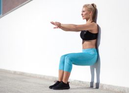 woman wall sit exercise, demonstrating how to get rid of thigh fat fast