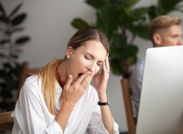 woman wondering why am I always tired, yawning at work