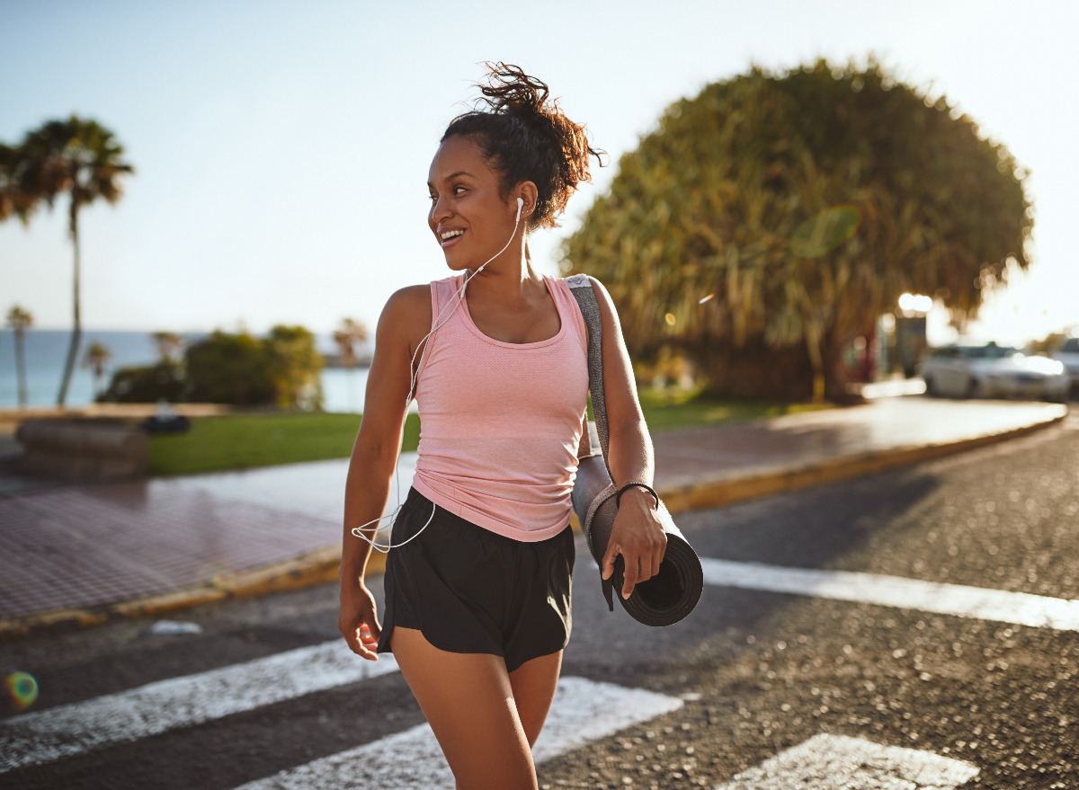 young woman carrying yoga mat, parked further from class to lose weight without exercising