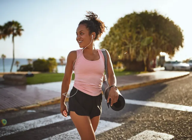 young woman carrying yoga mat, parked further from class to lose weight without exercising