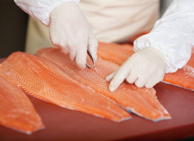 worker deboning salmon at fish market