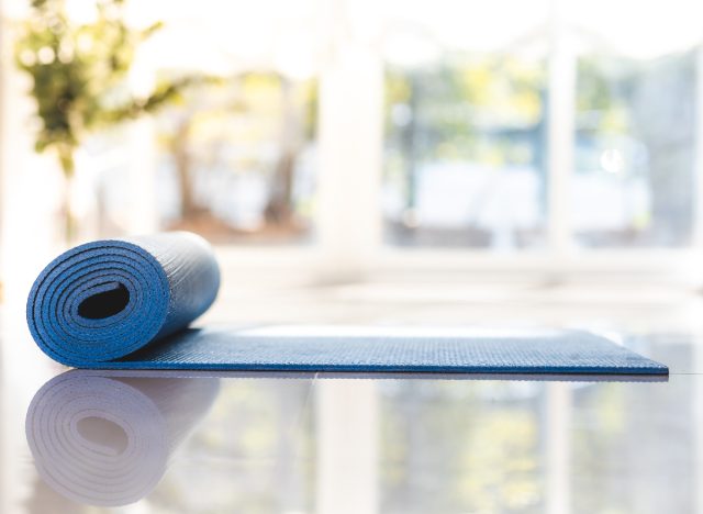 yoga mat being rolled out in bright room