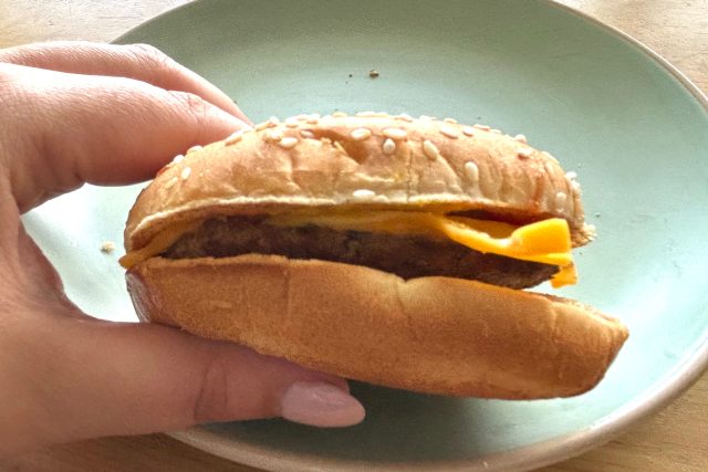 hand holding a burger king cheeseburger.
