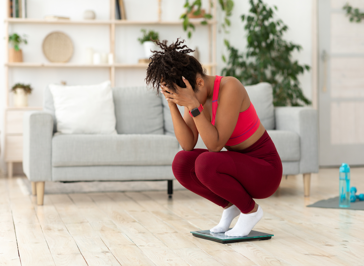 Woman crouched on scale, weight loss