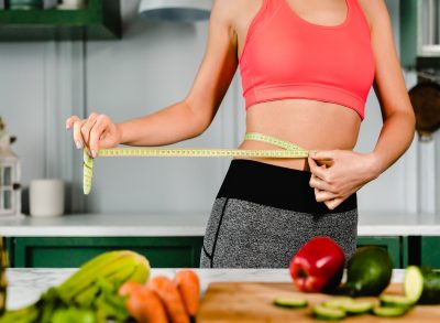 Woman with measuring tape and vegetables