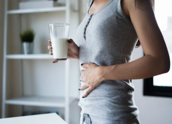 Woman holding stomach, drinking milk