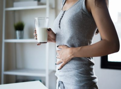 Woman holding stomach, drinking milk
