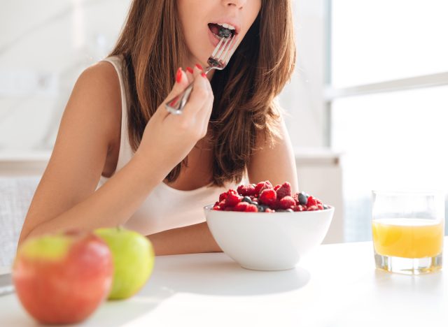 Woman eating bowl of fruit