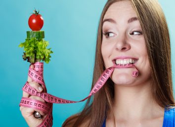 Woman with measuring tape and vegetables
