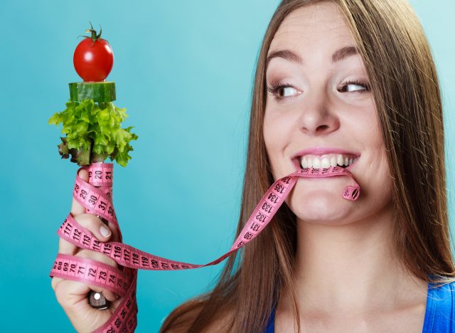 Woman with measuring tape and vegetables