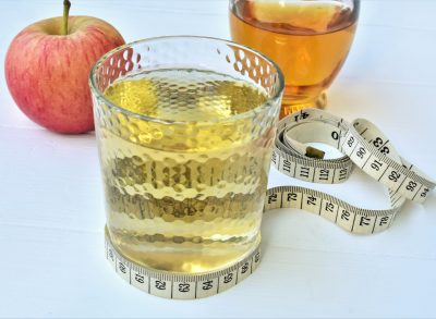 apple cider vinegar in glass with measuring tape
