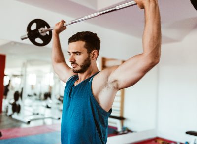 man doing barbell press to get rid of a beer belly