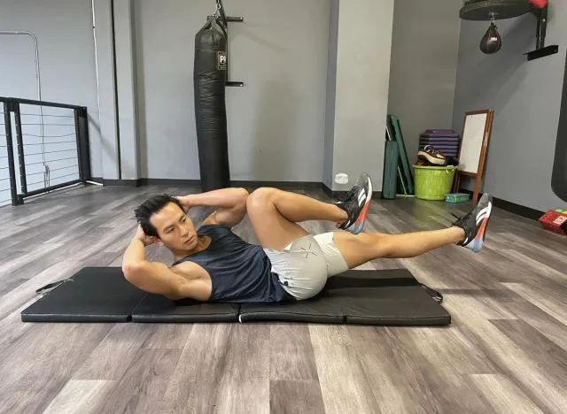 trainer demonstrating bicycle crunch exercise