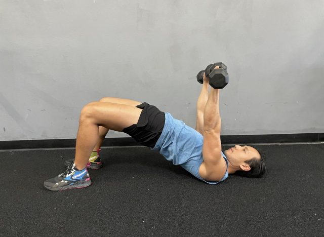 trainer doing bridge dumbbell floor press