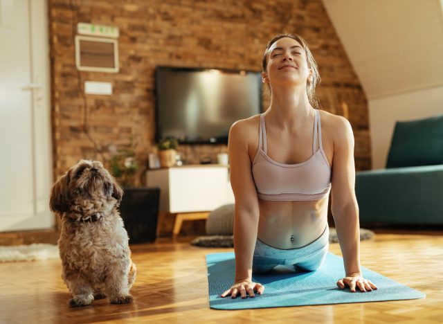 woman doing yoga with her dog, doga, indoors