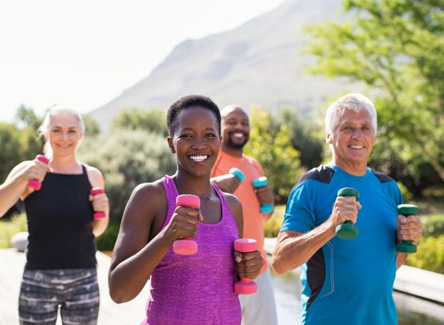 group of active people using dumbbells during walking workout outside, aging you faster