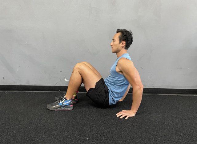 trainer doing floor dips, demonstrating exercise to get rid of bat wings