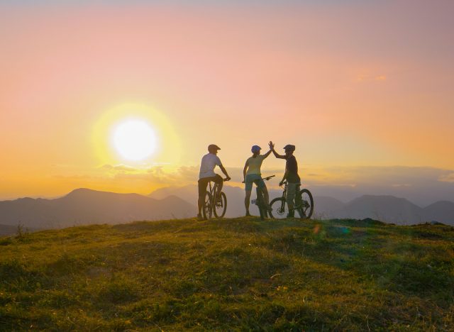 los ciclistas chocan los cinco en la cima de la montaña, hacen ejercicio para perder pulgadas de la cintura