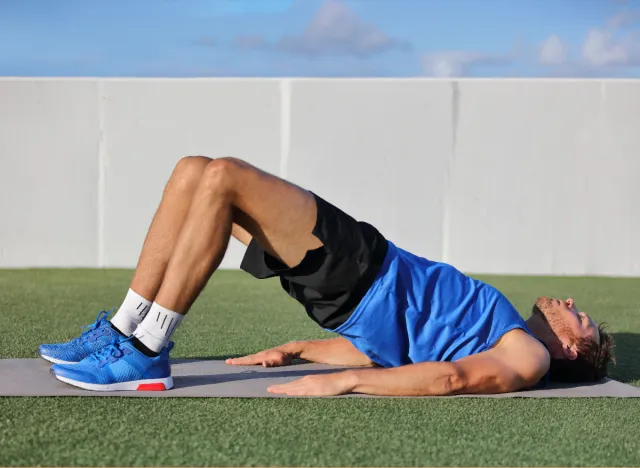 man doing glute bridge march to get a flatter stomach