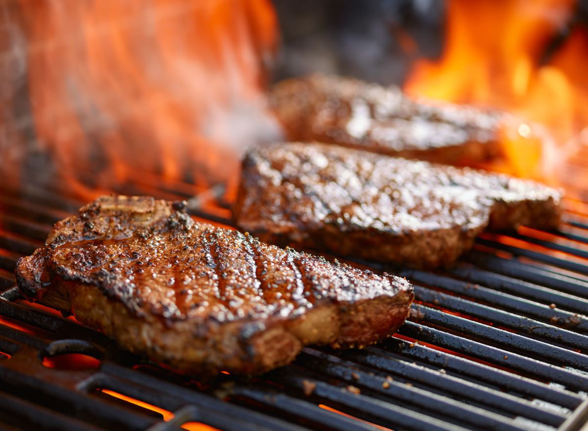 grilling steaks on flaming grill