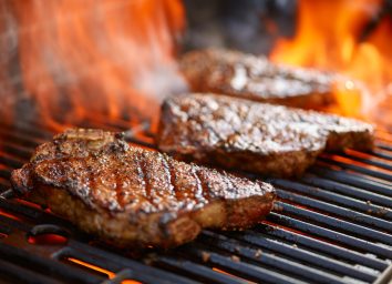 grilling steaks on flaming grill