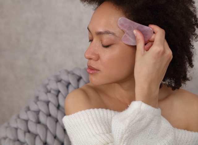 woman using gua sha stone to fight signs of aging skin