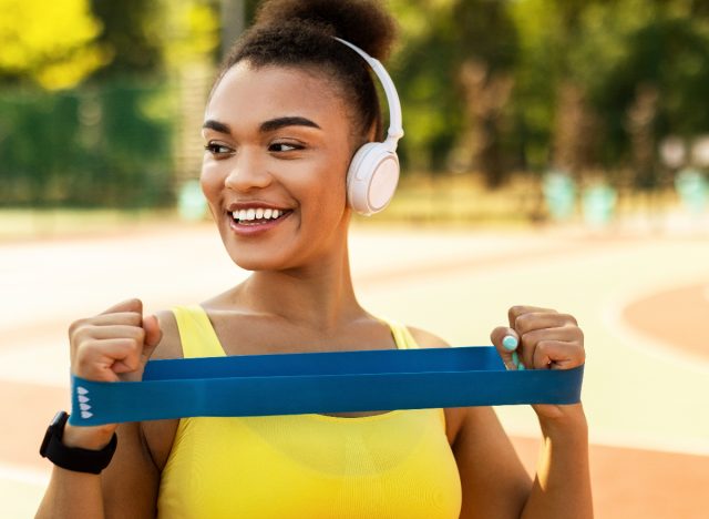 sporty woman with loop resistance band on track