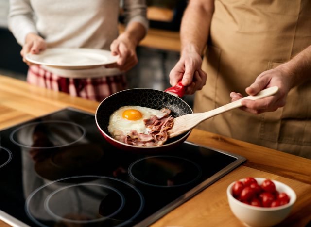 a man cooks bacon and eggs