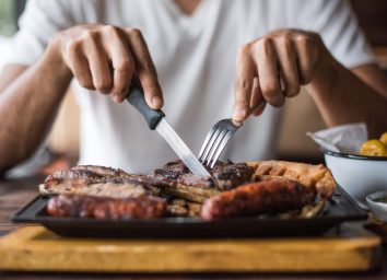 man cutting grilled meat