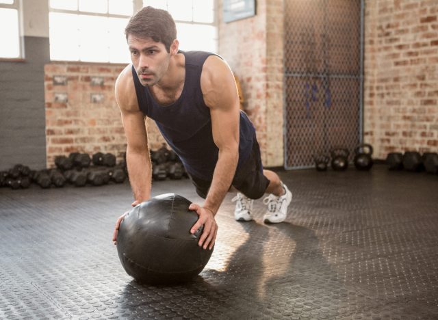 man performing medicine ball exercise to burn gut fat